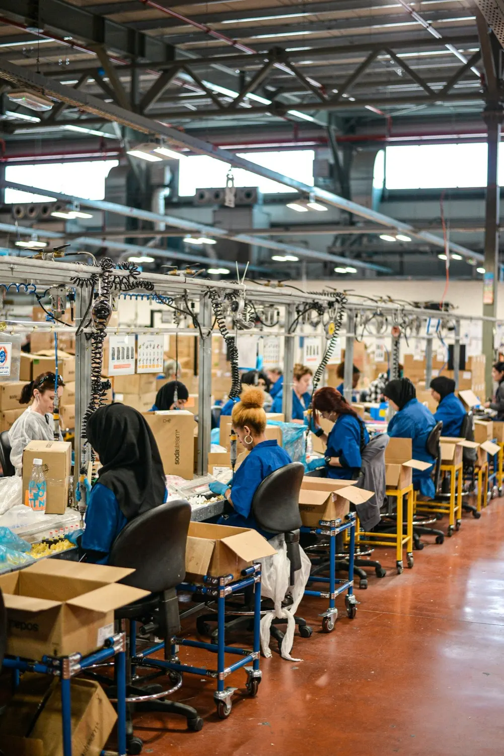 Workers assembling and packing products along a factory production line