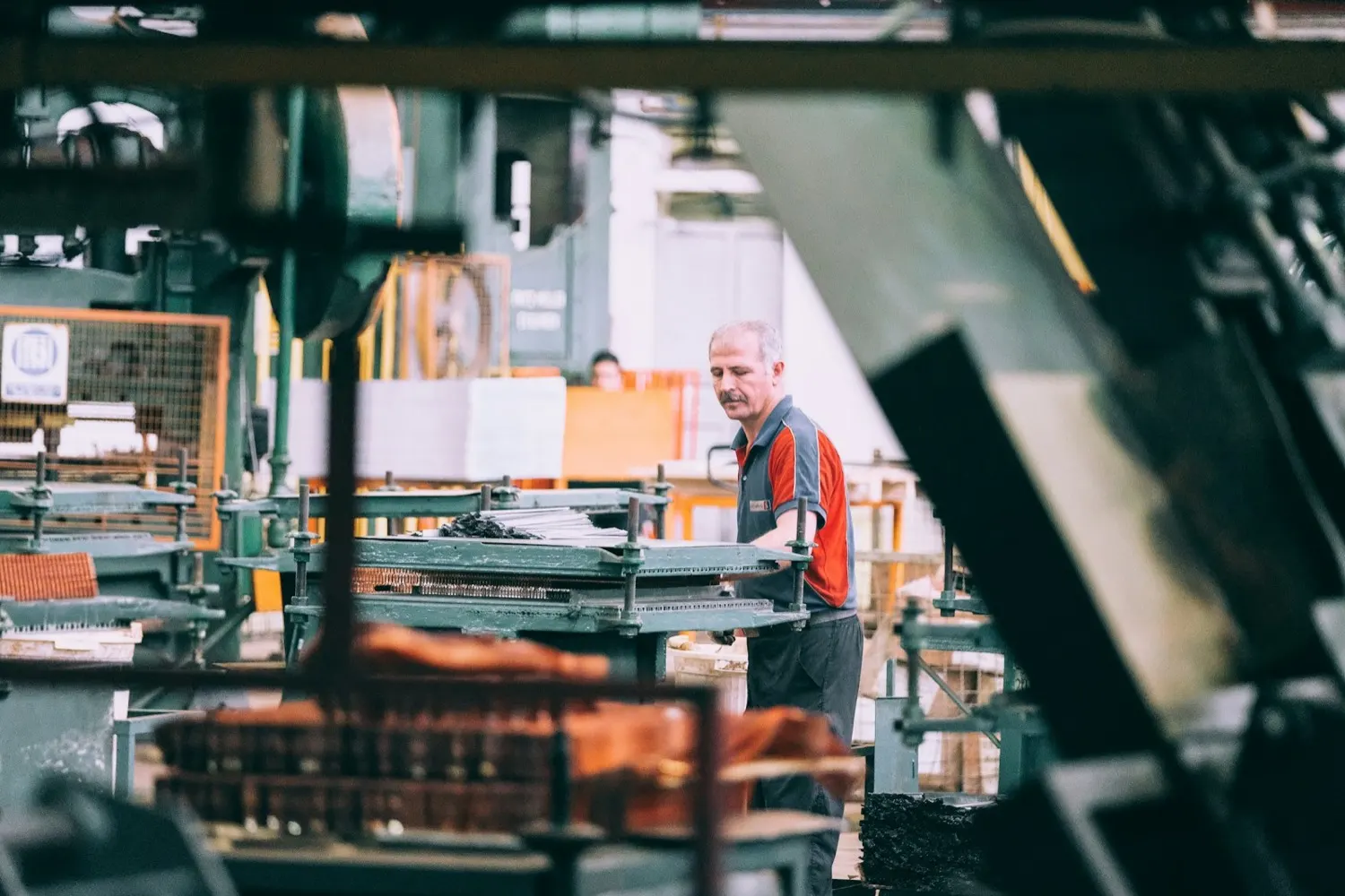 A worker operating machinery on the floor of a metals processing plant