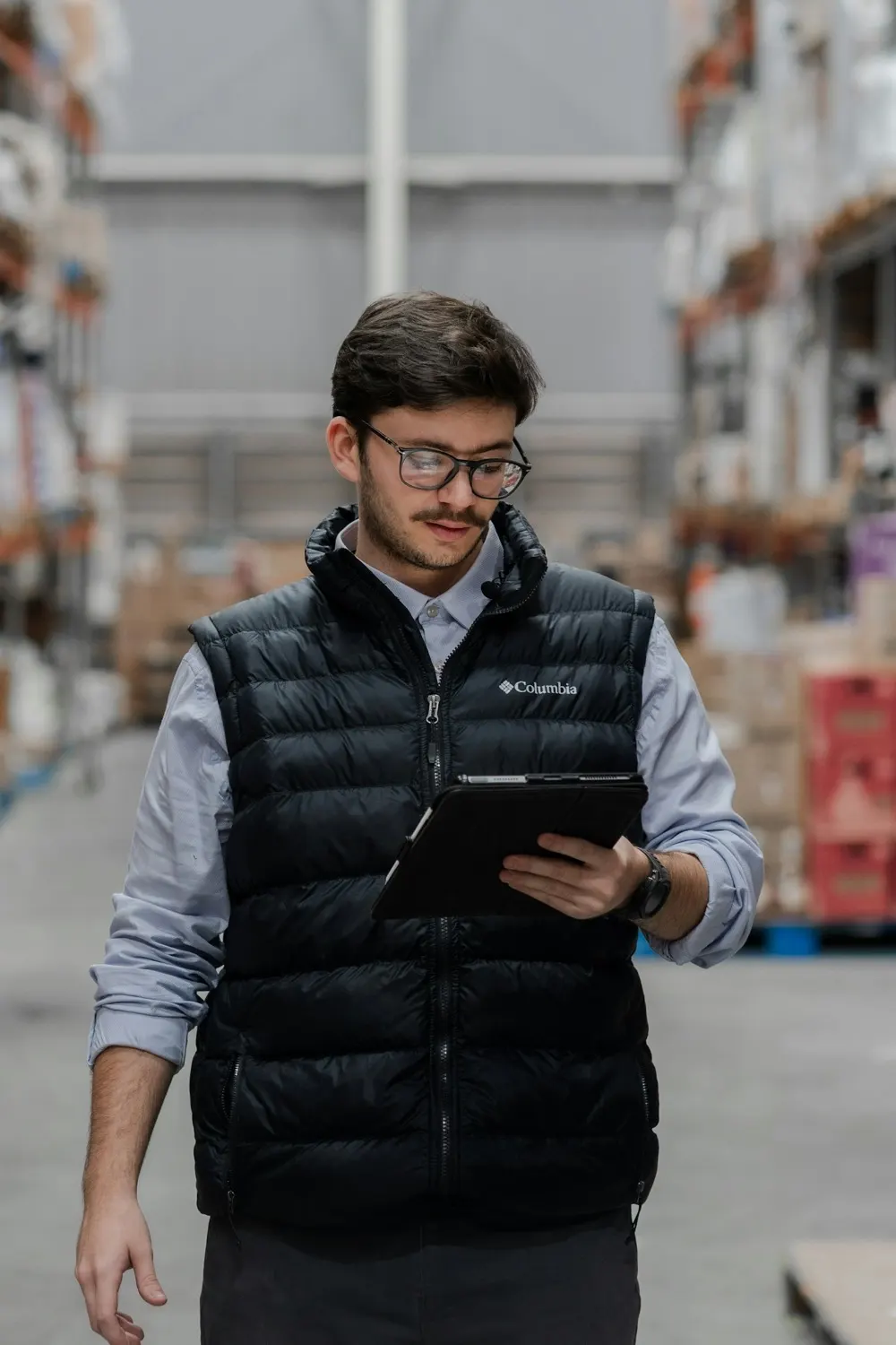 An operations manager reviewing figures on a tablet in a warehouse